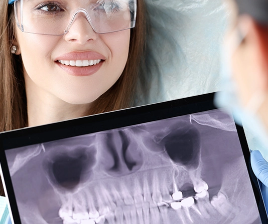 Woman in dental chair discussing x-rays with dentist
