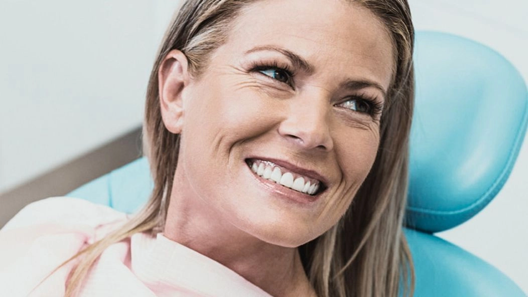 An image of a woman on a dental chair smiling 