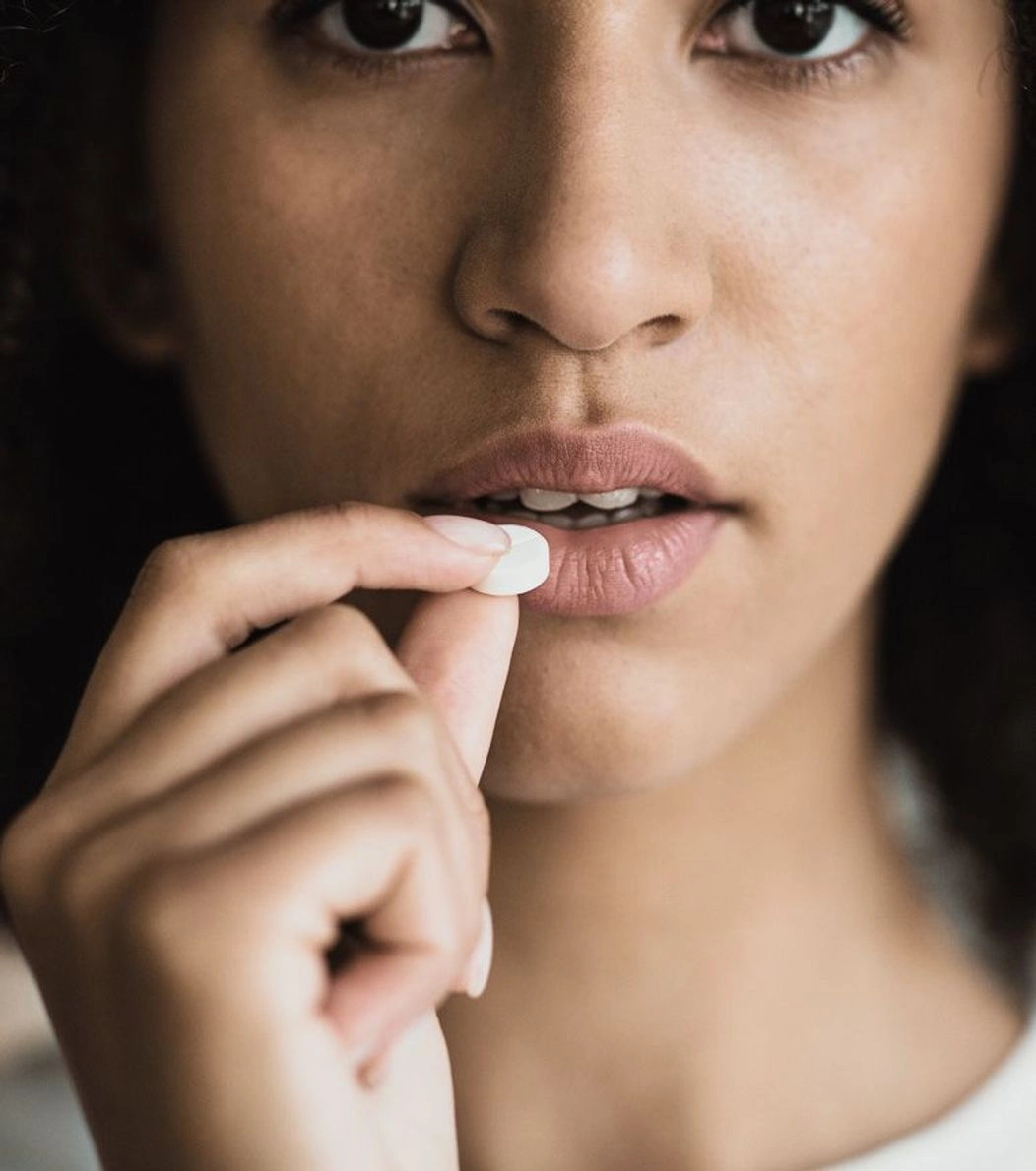 An image of lady holding a pill