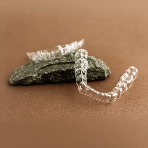Two clear aligners laying on a rock.