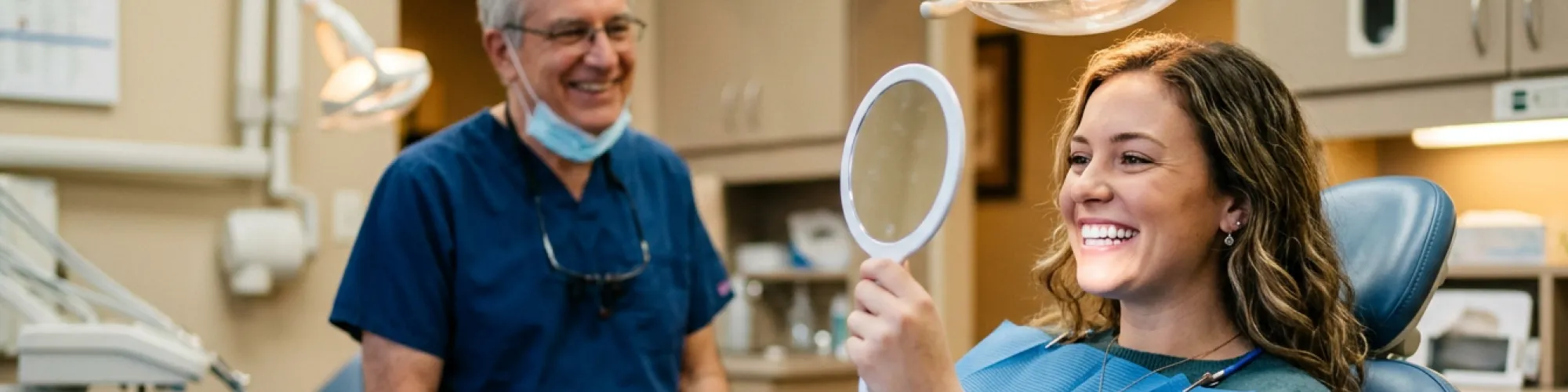 Woman smiling into hand mirror.