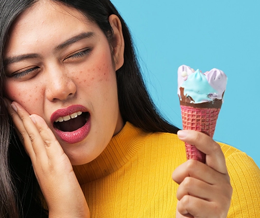 Woman eating ice cream and suffering discomfort and oral sensitivity
