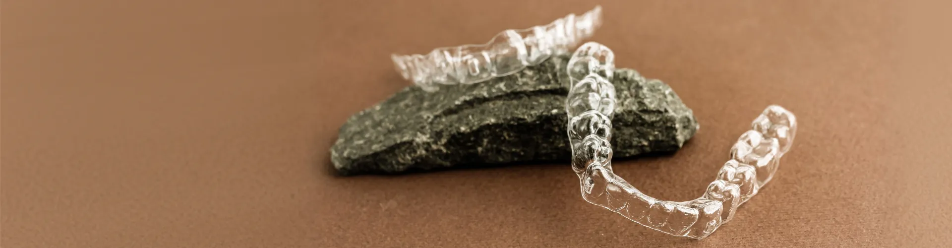 Two clear aligners laying on a rock.