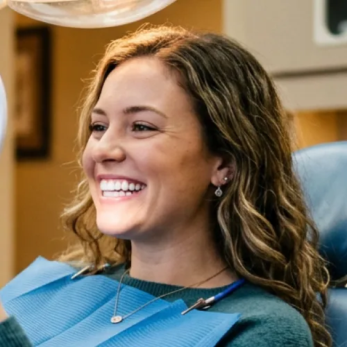 Woman smiling into hand mirror.