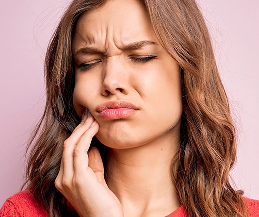 Woman clutching jaw experiencing tooth or gum pain
