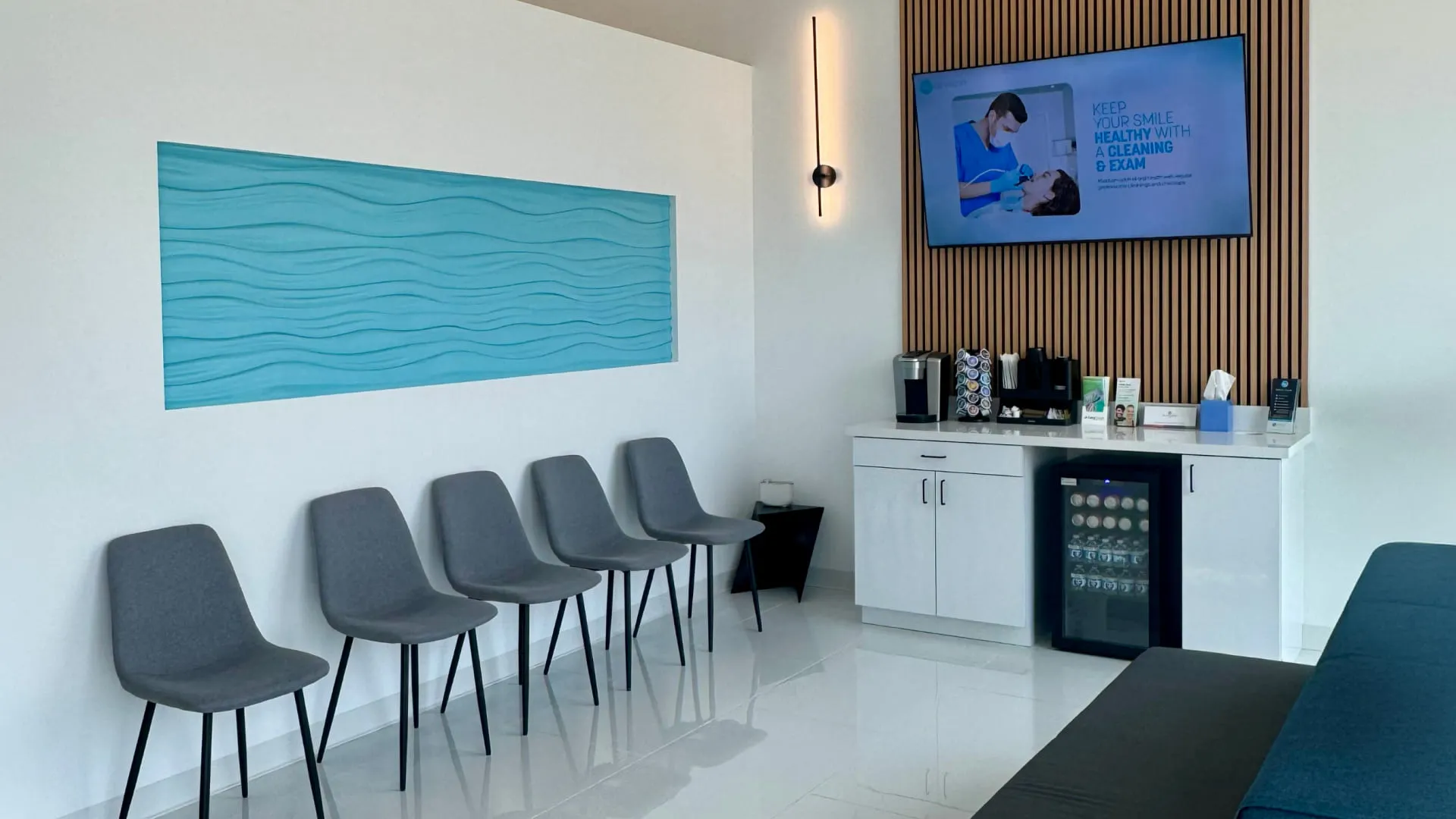 NuDentistry waiting area with gray chairs and blue wave wall art
